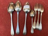 five spoons and a fork on a red surface