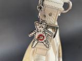 a small teddy bear on a white shoe with a red button