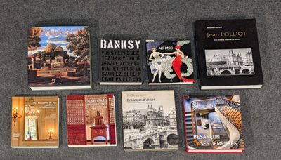 Plusieurs livres sont alignés sur une table devant un fond gris.