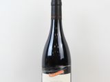 une bouteille de vin rouge posée sur une table blanche