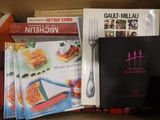 de nombreux livres de cuisine dans une boîte, avec une fourchette et un couteau