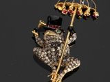 une broche représentant une grenouille avec un haut-de-forme et un parapluie