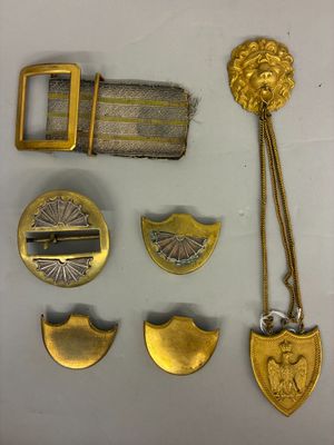 quelques objets en métal doré sont posés sur une surface blanche