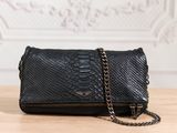 the black snake skin clutch bag is on a wooden table
