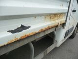 a rusted white truck parked on the side of the road
