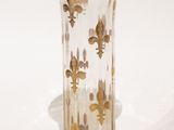 un vase en verre orné de fleurons dorés sur un fond blanc