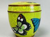 boîte en forme de papillon jaune et bleu avec couvercle, posée sur une surface blanche