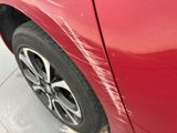 a close up of a red car with a denting on it