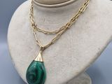 un collier vert et or avec un pendentif en forme de larme sur un mannequin