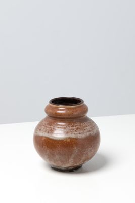 un petit vase marron posé sur une table blanche