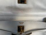 a close up of a white purse with a gold handle