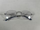 des lunettes posées sur une surface blanche, avec une chaîne autour de la monture