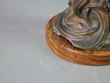 a statue of a woman sitting on top of a wooden base