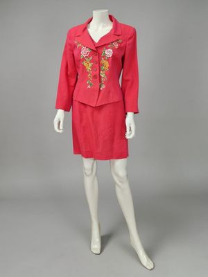 un mannequin vêtu d'une robe rouge et d'une veste ornée de fleurs brodées