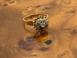 a gold ring with a diamond sitting on a wooden table