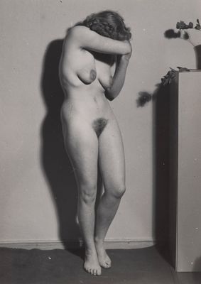 an old black and white photo of a naked woman leaning against a wall