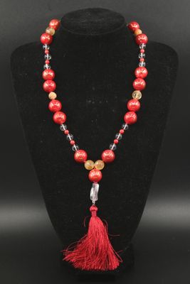 a red beaded necklace with a tassel on a black mannequin