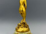 une statue en or représentant une femme debout sur un socle en marbre