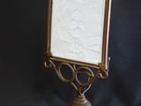 brass frame with a picture of a woman on it on a black background