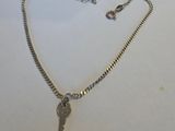 un gros plan d'un collier en argent avec une clé suspendue à une chaîne
