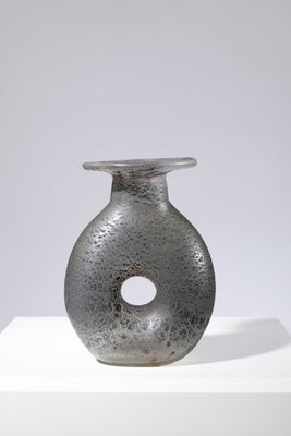 vase gris posé sur un socle blanc, sur fond gris