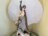 a figurine of a woman with a peacock on top of a glass table
