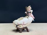 une petite figurine représentant une petite fille assise sur une coquille d'œuf