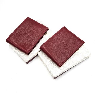two leather wallets sitting on top of each other on a white surface