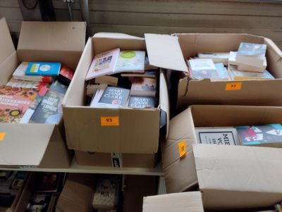 de nombreuses caisses de livres posées sur une étagère dans une pièce