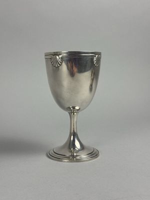 un gobelet en argent posé sur une surface blanche