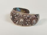 a close up of a silver bracelet on a white surface