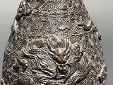 an image of a silver vase with a dragon design on it