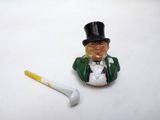 a small figurine of a man with a top hat next to a golf tee