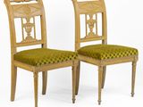 pair of chairs with green upholstered cushions and carved backrests