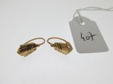 une paire de boucles d'oreilles en or avec une étiquette de prix posée sur une table blanche