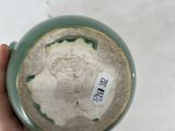 a person holding a green vase with a label on it