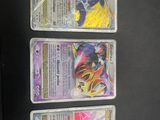 three pokemon cards are on a black surface with a black background