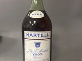 Des bouteilles de vin sont posées sur une table devant un fond gris.
