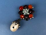 an image of a brooch with beads and stones on a blue surface