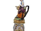 a figurine of a woman sitting on top of a vase