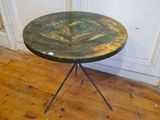 une petite table au plateau vert posée sur un parquet