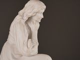a white statue of a woman sitting on a stool