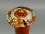 a red vase with a bird on top of it