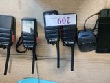 four walkie talkies are lined up on a table next to a cell phone