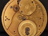 une image montrant un gros plan du cadran doré d'une horloge sur une surface noire