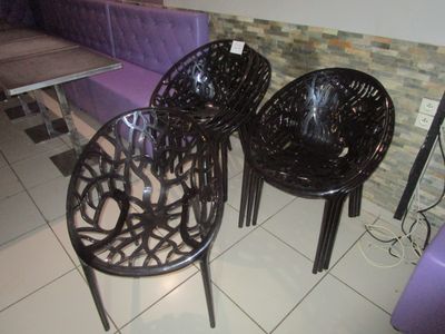 trois chaises en plastique posées sur un sol carrelé dans une pièce
