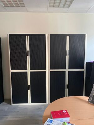 several black and white lockers in a room with a table and chair