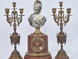 une statue représentant une femme, posée sur un socle à côté de trois chandeliers
