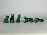 quatre figurines de chats verts assises les unes à côté des autres sur une surface blanche