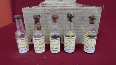 five miniature bottles of liquor in front of a box